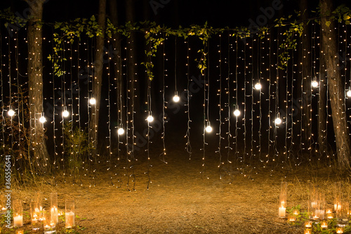 Wedding ceremony evening with candles and lamps in the coniferous pine forest