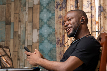 young black man using earphones to listen while making a phone call