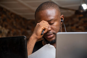 stressed and tired young black man working with his laptop