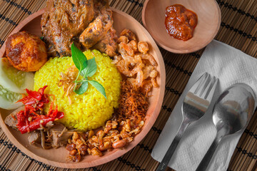 Wall Mural - Indonesian Style Complete Meal with Yellow Rice, Grilled Chicken with Peanut Sauce, Dry Shrimp, Fried Soybeans with Peanut, and Egg with Chili