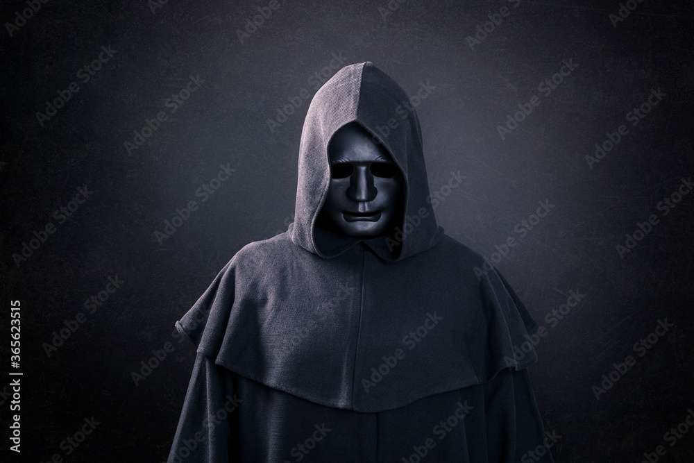 Scary figure with mask in hooded cloak in the dark - obrazy, fototapety, plakaty 