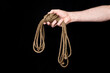 A man holds in his hand a coil of rope. Isolated on a black background.