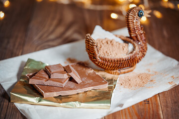 Chopped chocolate with cocoa on wooden table