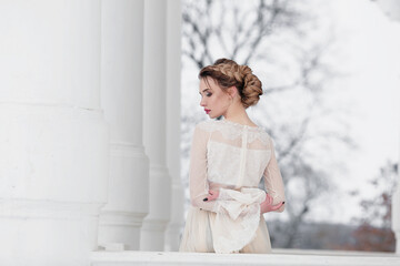 Close-up portrait of blonde woman from the back with perfect wedding hairstyle in white long dress posing for wedding magazine. Bride concept. 