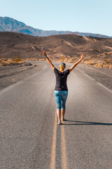 Wall Mural - A woman walking barefooted on an empty road in the Death Valley