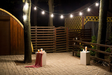 Wall Mural - Garden with a wooden gazebo with lights, candles at night at a wedding