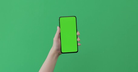 young female hand touch smartphone with green screen on green background