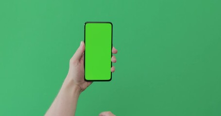 Wall Mural - Young man hand use smartphone with green screen on green background