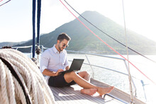 Man Working On Yacht Office With Laptop. Traveling On Sailboat. Traveler Using Tablet Computer. Freelancer Workplace In Self Isolation, Social Distance. Successful Business Lifestyle.