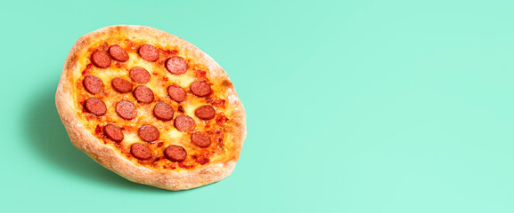 Wall Mural - Pizza pepperoni on a green background. Whole pizza salami with copy space