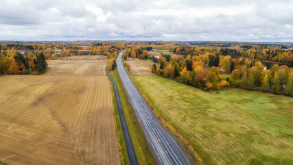 Wall Mural - View of agricultural fields, autumn forest and road in Finland. Aerial panorama of beautiful farmlands.