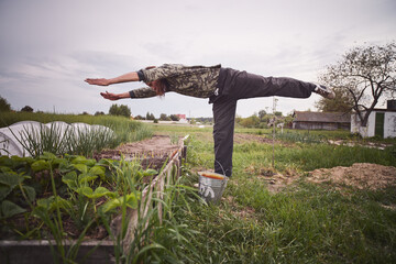 Sticker - Young Caucasian rural man planting garlic in the ground at his farm.