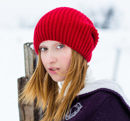 The beautiful blonde girl in red hat in the forest. Girl in winter. White snow. Little Red Riding Hood