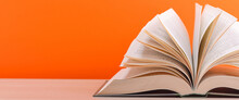 The Book Is Open, Lying On The Table, Sheets Fanned Out On A Orange Background.