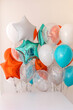 Composition of blue, silver, orange and transparent balloons with helium. Foil balloon in the shape of a star. The concept of decorating a room with helium balloons for holidays or birthdays