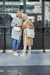 Two cheerful women posing at the photo camera in the outdoors