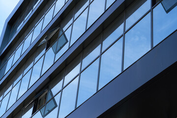 facade of a modern building on a bright Sunny day, blue sky and clouds reflecting in a glass, beautiful exterior of the new building