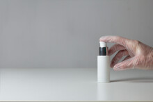 A Finger Presses A Jar Of Disinfectant Gel On A Gray Background And A White Table.