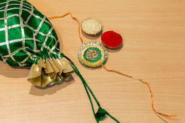 Indian festival, Raksha Bandhan background with an elegant colorful Rakhi, Gift, Rice Grains and Kumkum. A traditional Indian wrist band which is a symbol of love between Brothers and Sisters.