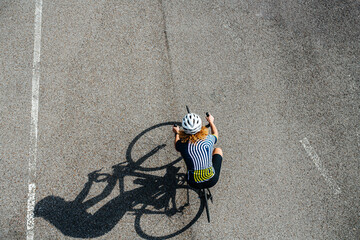 Woman cycling on a professional bike in a white helmet, shot from above