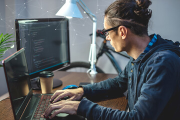 Male programmer is writing program code on a laptop at home. The concept of software development