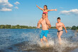 © Andrii - Happy family having fun on the beach running and jumping in the water at sunset. Vacation, sports, lifestyle.