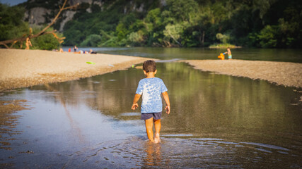 young boy walking in stream of river