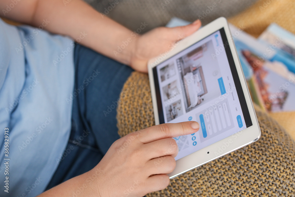 Woman with tablet computer booking room in hotel at home