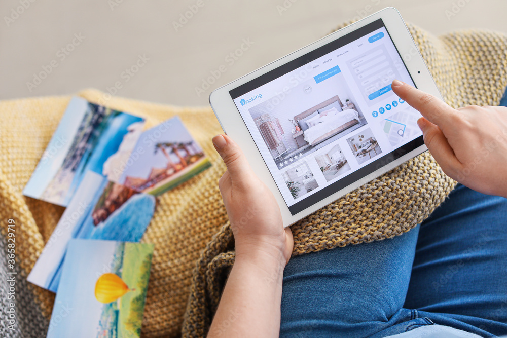 Woman with tablet computer booking room in hotel at home