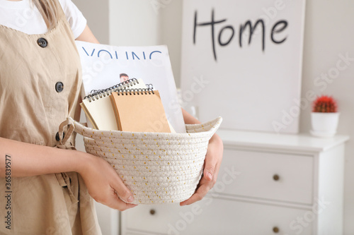 Fotografía Woman holding wicker basket with items in room