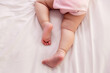 Adorable innocent baby try to crawling on bed that the first time infant baby crawl. Lovely toddler girl wear pink baby dress. Toddler child trying to use leg for lifting legs and body. Close up legs