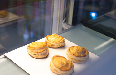 Wall Mural - Fresh 4 puff scones on the plate at the bakery cafe shop, bread on the white board, Four freshly homemade baked puffs in a cafe