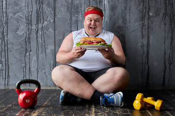 overweight caucasian man can not adhere to a healthy lifestyle and diet, doing sport exercises and at the same time eat unhealthy food