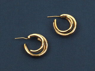 Gold women`s earrings on dark blue background