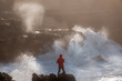Fearless young female photographer surrounded by raging waves at rocky Oregon coast