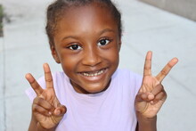 Close Up Of Young Child Holding Up Peace Signs With Both Hands
