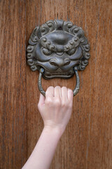 Wall Mural - Action of people hand's is pulling the wooden door handle to opening the Chinese design-style door. Close-up and selective focus on hand's part.