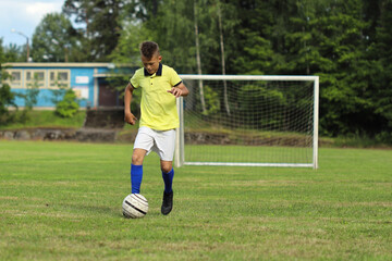 Aufkleber - handsome boy soccer player in a yellow t-shirt on the soccer field plays with a ball