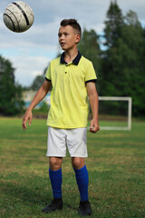 Aufkleber -  boy soccer player in a yellow t-shirt on the soccer field juggles the ball