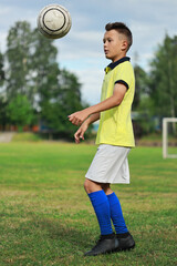 Aufkleber -  boy soccer player in a yellow t-shirt on the soccer field juggles the ball