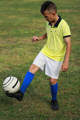 Aufkleber -  boy soccer player in a yellow t-shirt on the soccer field juggles the ball