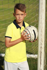 Aufkleber -  boy football player in a yellow t-shirt stands near the goal with the ball