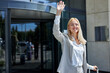 © Roman - attractive smiling woman greeting someone after leaving hotel, say hello to doorman or taxi