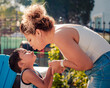 A latina mother is leaning to kiss her son on the lips at a backyard pool party