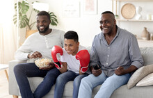 Black Dad, Son And Grandfather Watching Boxing Match On Tv And Cheering