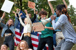 © Roman - diverse mixed race people with posters agitating Marijuana being legal, group of youth in the park, holding placards and megaphone loudspeaker