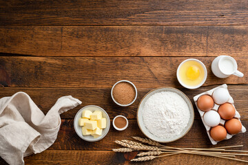 Wall Mural - Ingredients for baking on a rustic wooden background. Flour, eggs, butter, sugar and other ingredients for baking a cake, sweet bread pastry or cookies