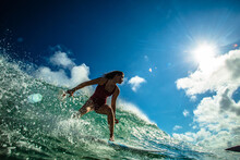 Professional Surfer Girl Riding Wave On Surfing Board Under Bright Sun On Background.