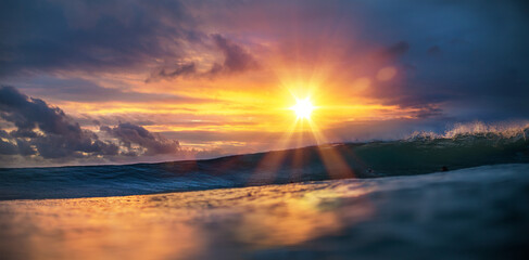 Wall Mural - sunset sea tropical background, surfing wave incoming with surfers on ocean water surface