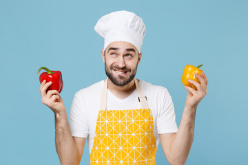 Wall Mural - Pensive young bearded male chef cook man in apron white t-shirt toque chefs hat isolated on blue background. Cooking food concept. Mock up copy space. Hold skewer with fresh vegetables bell peppers.